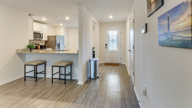 A modern kitchen with a microwave, refrigerator, and bar stools. - Sleek + Convenient Palm Bay Stay: Bring Your Pet! (Palm Bay)