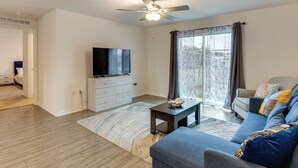 A living room with a ceiling fan, a flat-screen TV, a sofa, and a coffee table. - Sleek + Convenient Palm Bay Stay: Bring Your Pet! (Palm Bay)