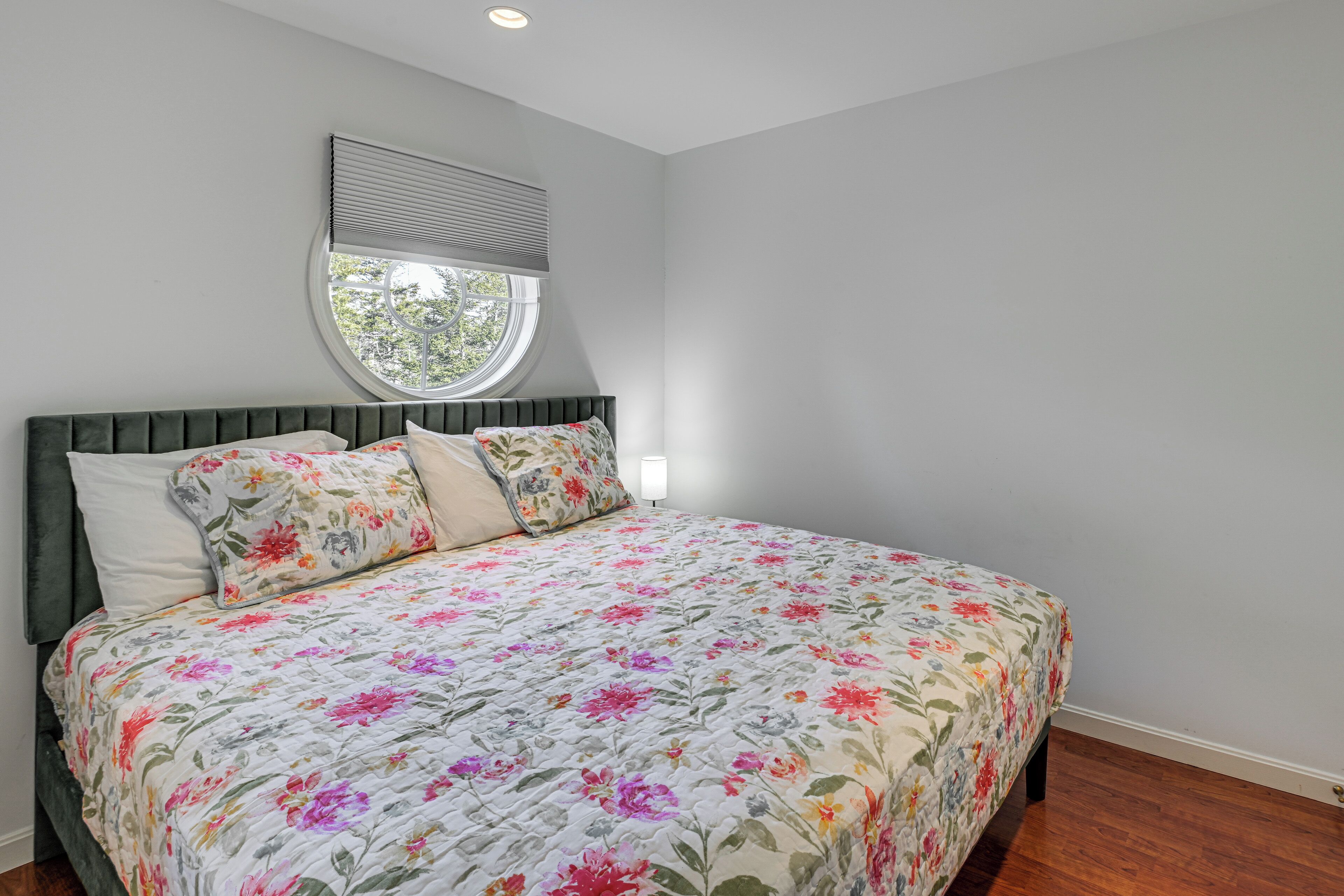 A bedroom with a bed, a window, and a wall-mounted light.