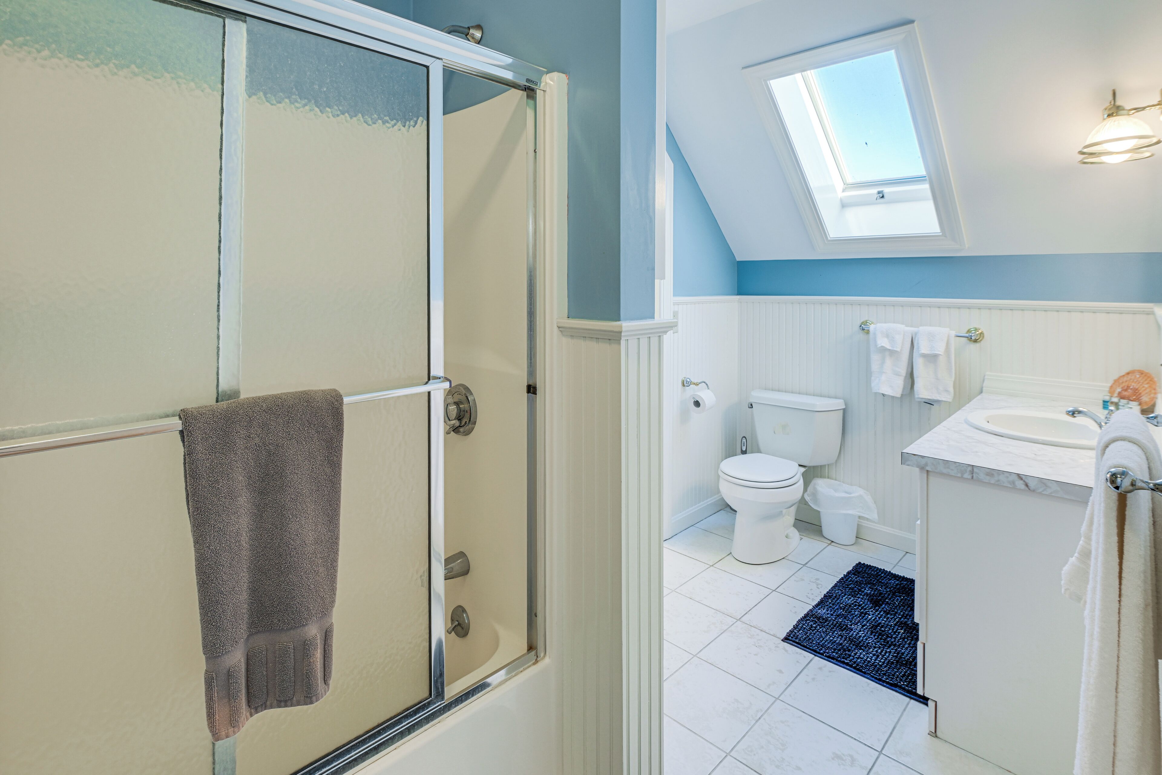 Une salle de bain équipée d’une douche, de toilettes, d’un lavabo et d’une lucarne.