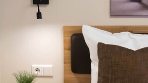 A hotel room with a bed, a nightstand with a plant and an apple, a wall-mounted power outlet, and a framed picture above the bed. - Comfortable single room 7 in the historic center of Heidenheim (Heidenheim)