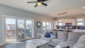 A spacious living room with a large sofa, a coffee table, and a ceiling fan. - New Oak Island Home w/ Ocean Views! (Oak Island)
