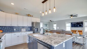 A modern kitchen with granite countertops, stainless steel appliances, and pendant lighting. - New Oak Island Home w/ Ocean Views! (Oak Island)