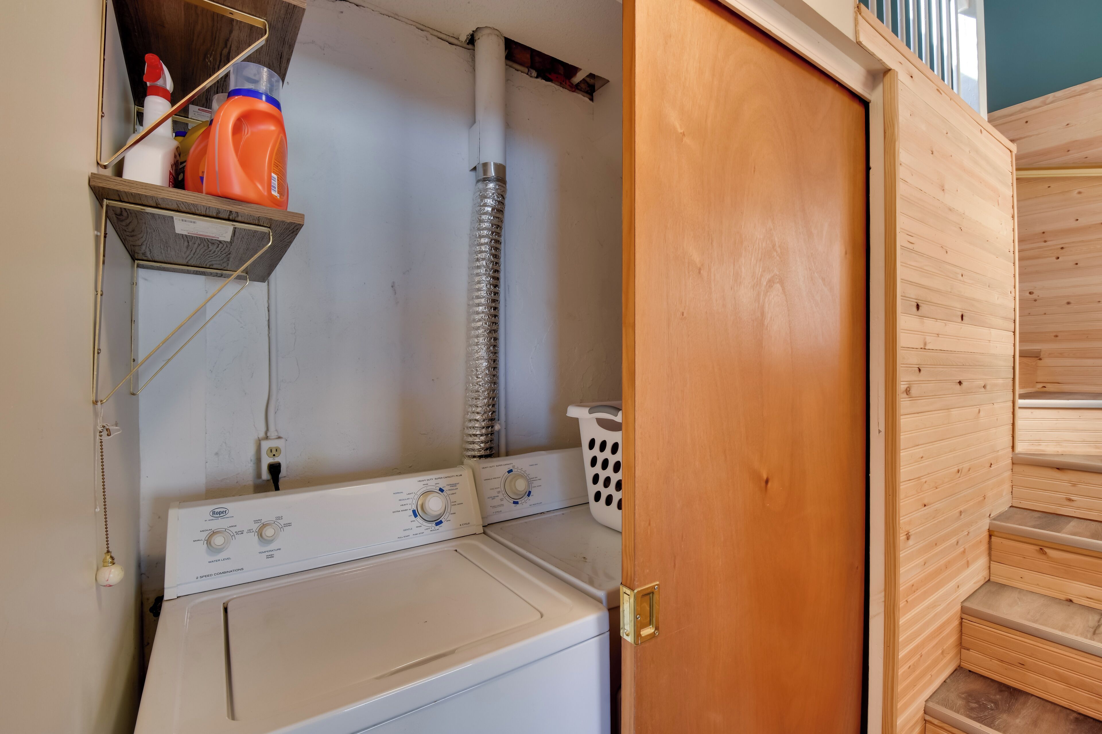 A laundry area with a washing machine, a dryer, and a shelf with cleaning supplies.