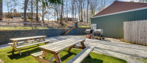 A backyard with a wooden picnic table, a barbecue grill, and a shed.