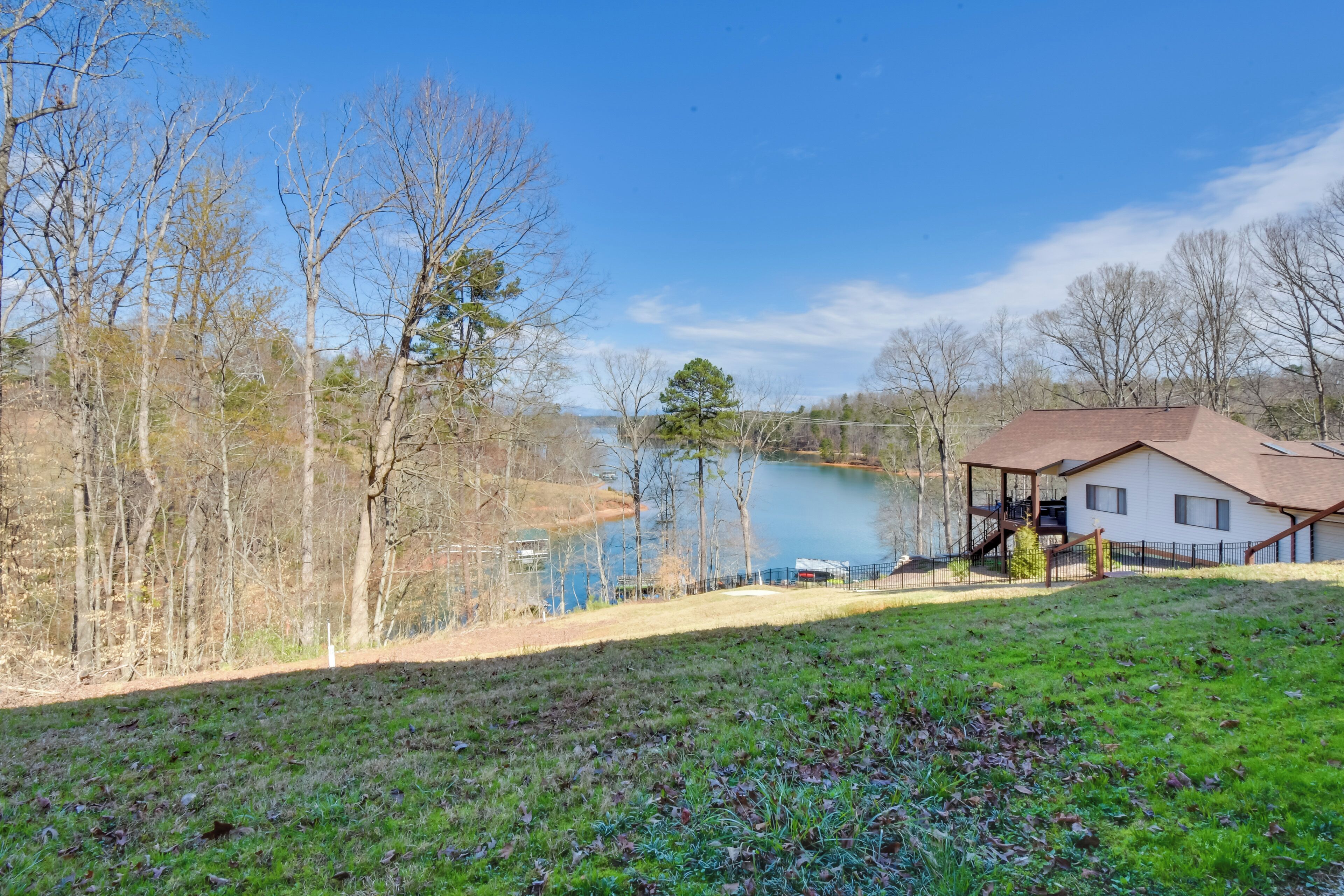 A house with a dock, a lake, and a grassy area.