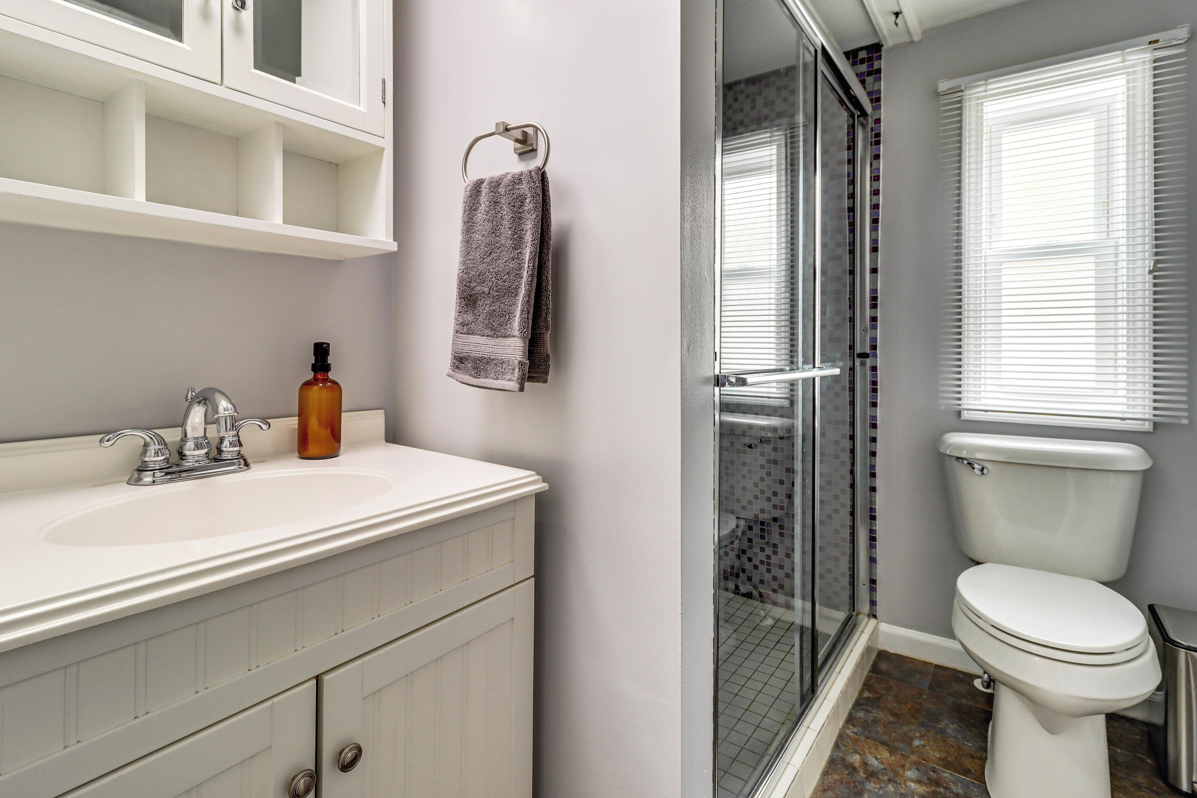 Une salle de bain avec un lavabo blanc, une douche en verre et des toilettes blanches.