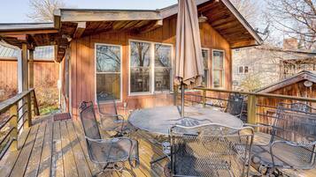 A wooden deck with metal chairs and a round table, overlooking a residential area.