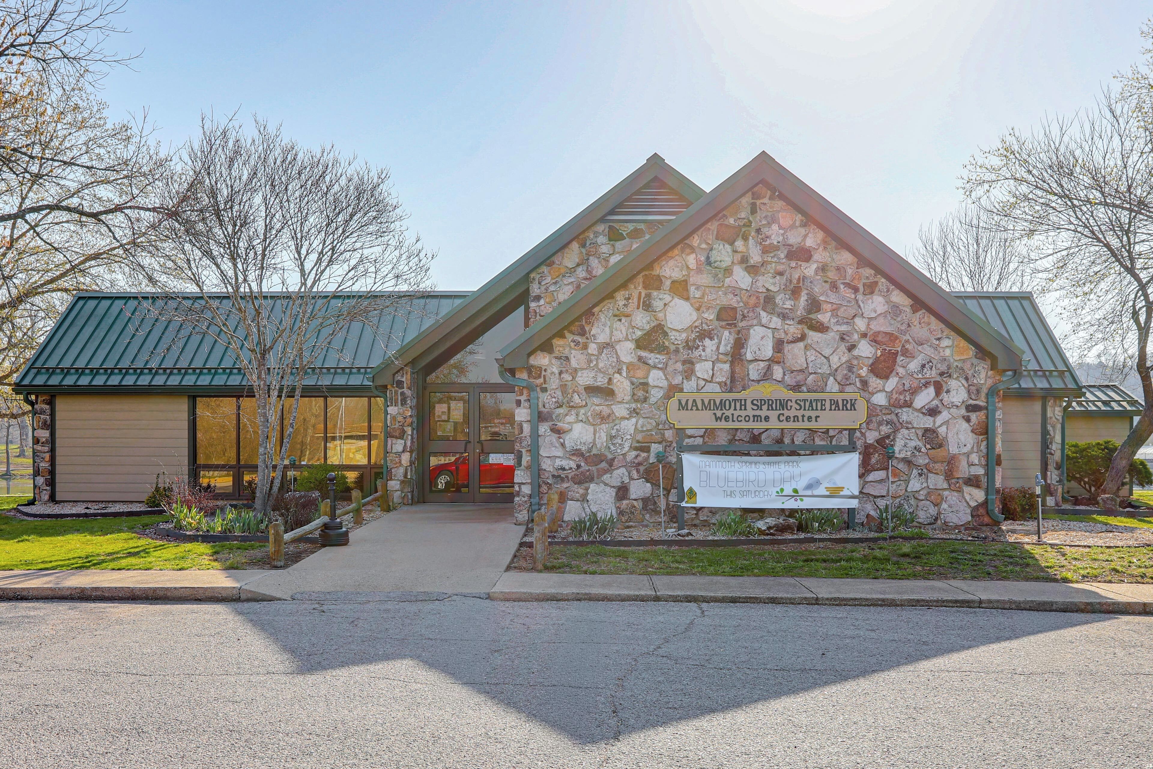 Een gebouw van steen met een bord waarop staat 'Mammoth Spring State Park Welcome Center'.