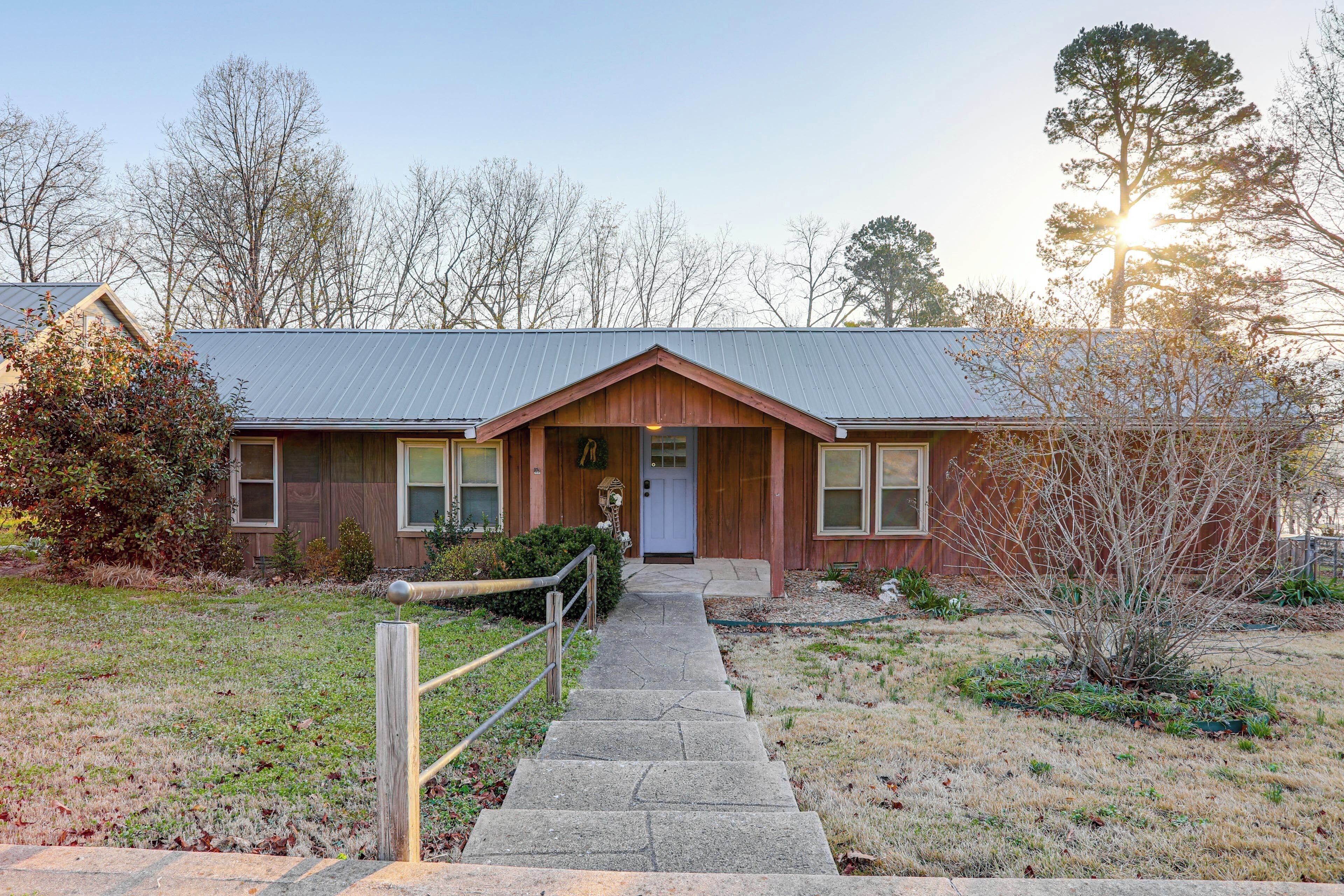 A two-story building with a front porch, a wooden door, and a metal roof.