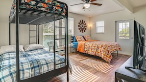 Ein Schlafzimmer mit Etagenbett, Schreibtisch, Fernseher und Deckenventilator.