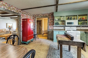 A kitchen with a red refrigerator, a microwave, and a stove. There is a dining table with chairs and a rug.