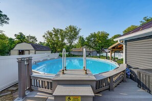 A swimming pool with a safety sign, surrounded by a deck and a covered area. - Near Pine Knob, Lakes & Trails! Ortonville Getaway (Ortonville)