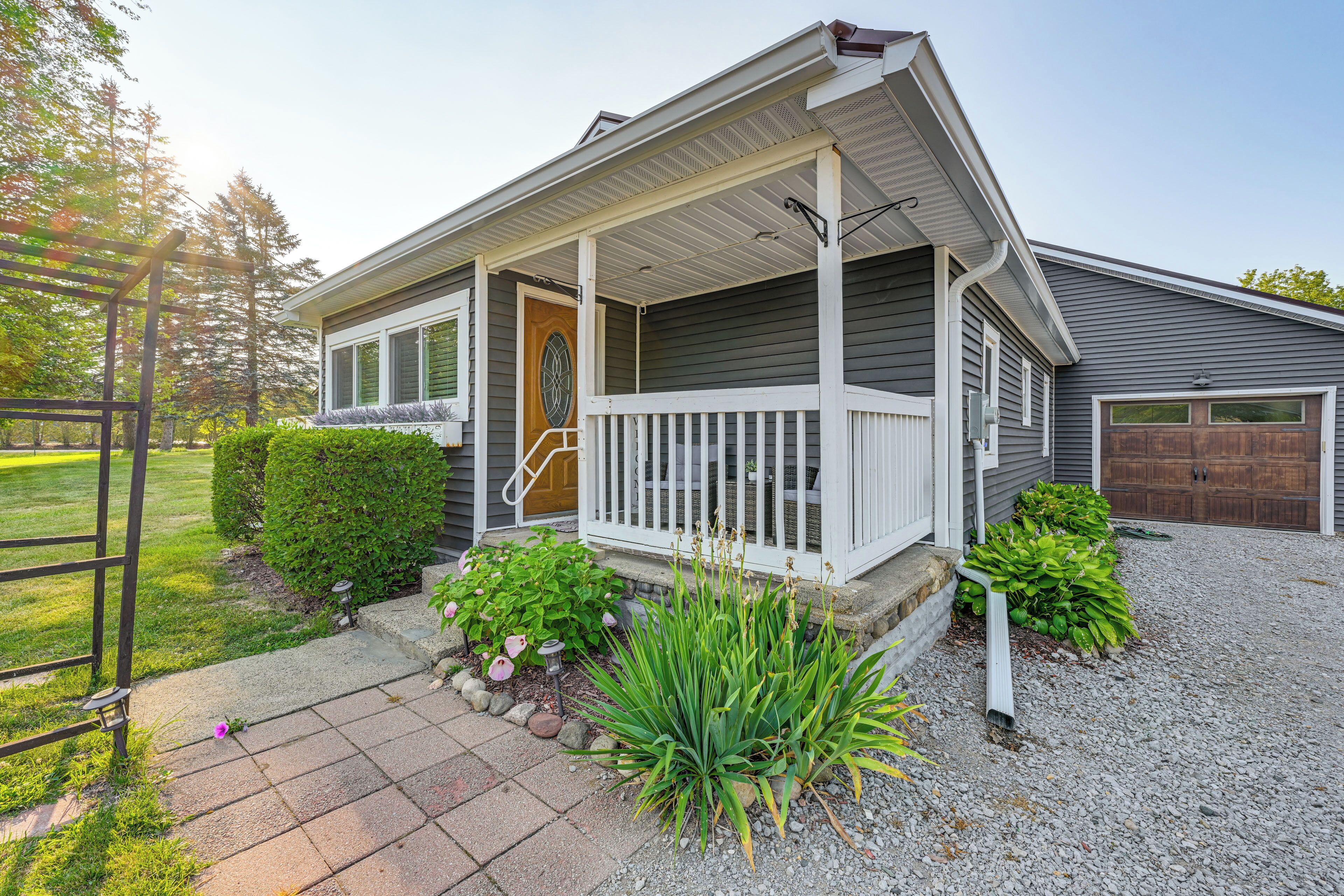 A two-story house with a covered porch, a garage, and a well-maintained front yard with plants and a gravel pathway.