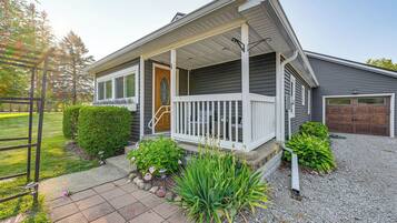 A two-story house with a covered porch, a garage, and a well-maintained front yard with plants and a gravel pathway.