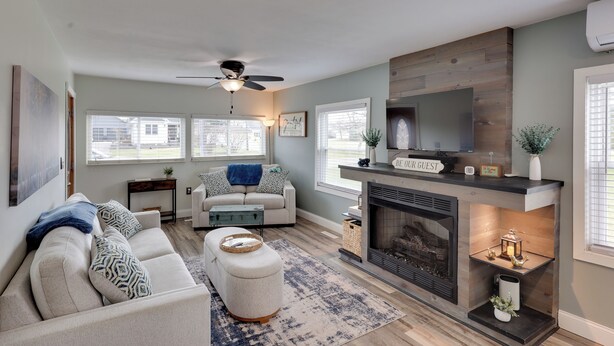 A living room with a fireplace, a ceiling fan, and a sofa. - Near Pine Knob, Lakes & Trails! Ortonville Getaway (Ortonville)