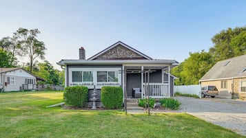 A two-story house with a front porch, a stone chimney, and a well-maintained lawn.
