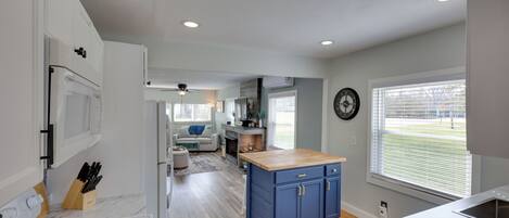A modern kitchen with a central island, white cabinets, and a dining area with a sofa and table.