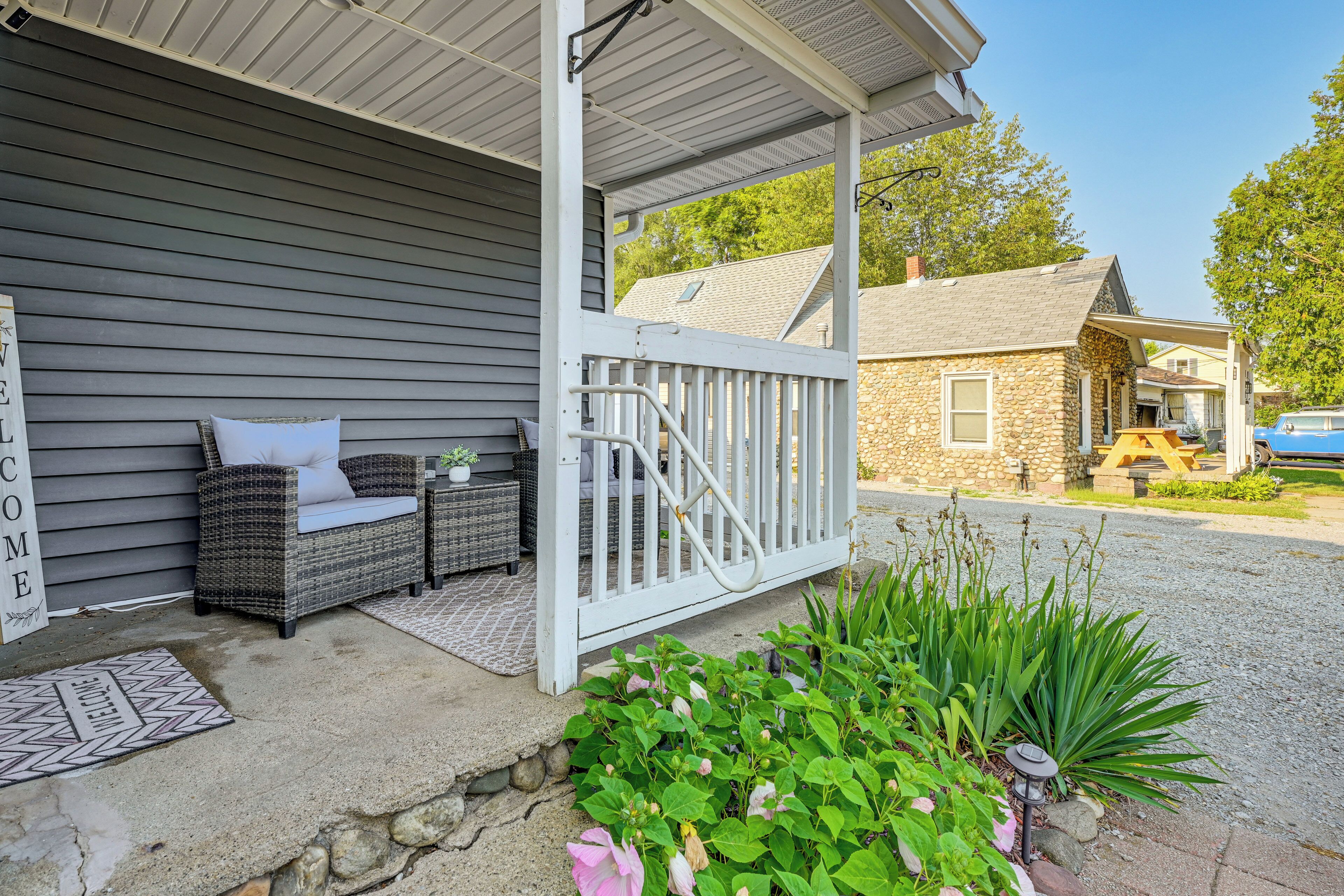 A covered porch with outdoor furniture, a stone wall, and a gravel pathway.