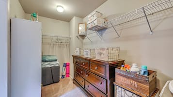 A bedroom with a bed, a dresser, a drying rack, and a wardrobe.