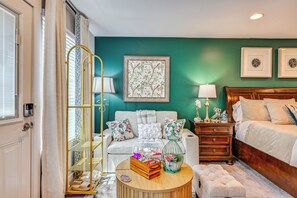 A bedroom with a bed, a nightstand, a dresser, a chair, a lamp, a picture frame, and a window with curtains. - King Studio Near Charlotte Speedway, Ev-l2 Charger (Concord)