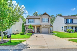 A two-story residential house with a stone facade, a front porch, and a driveway leading to the garage. - Deck, Patio! Charming Concord Studio Near Speedway (Concord)