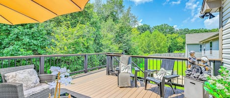 Une terrasse en bois avec des meubles d’extérieur, un parasol jaune et une statue.