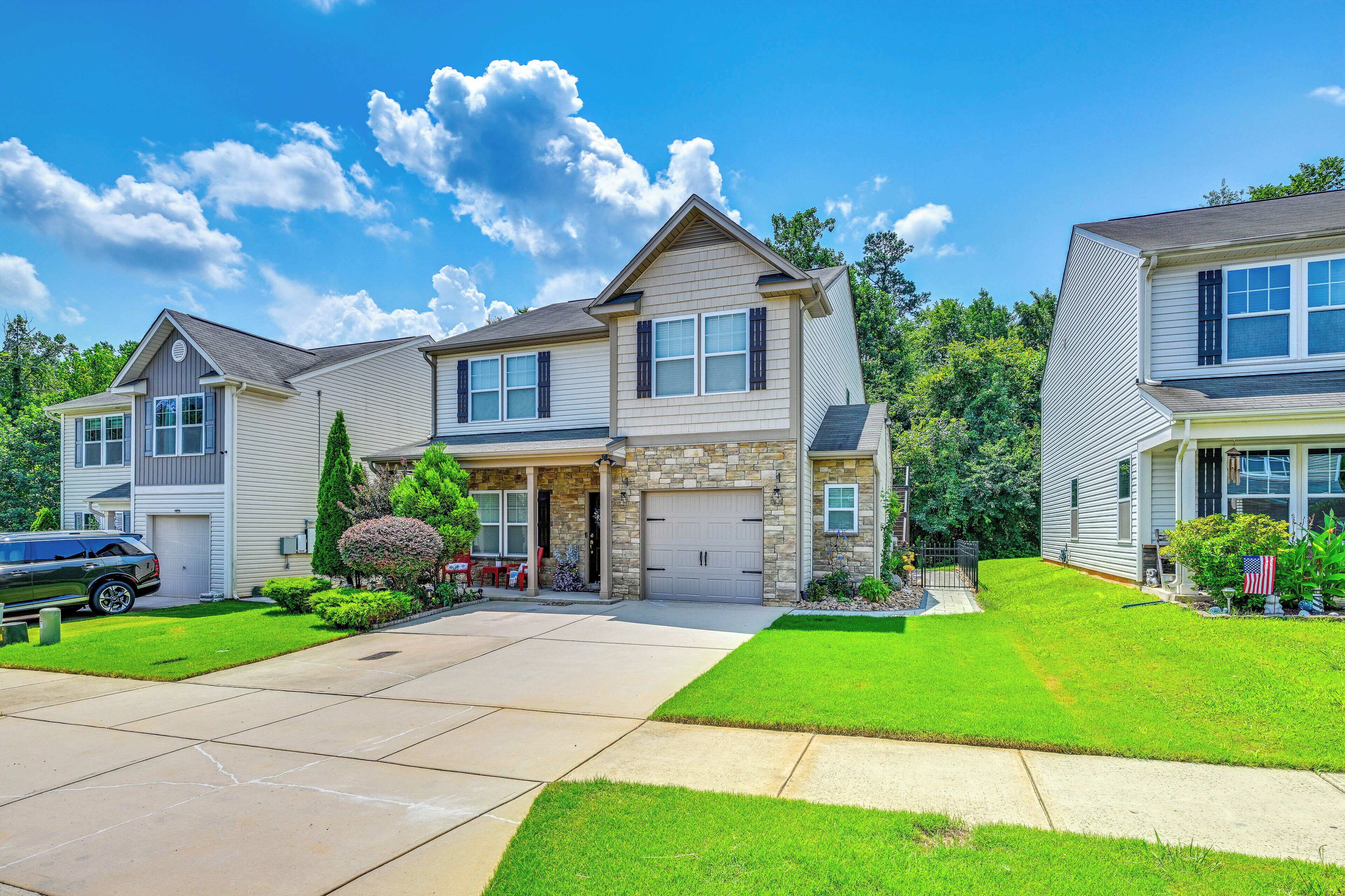 A two-story residential house with a stone facade, a garage, and a well-maintained lawn.