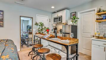 Cocina compacta con una isla central, taburetes de bar, microondas y refrigerador.