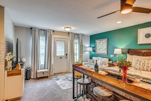 A well-lit room with a bar area, seating, and a door leading to another space. - Deck, Patio! Charming Concord Studio Near Speedway (Concord)