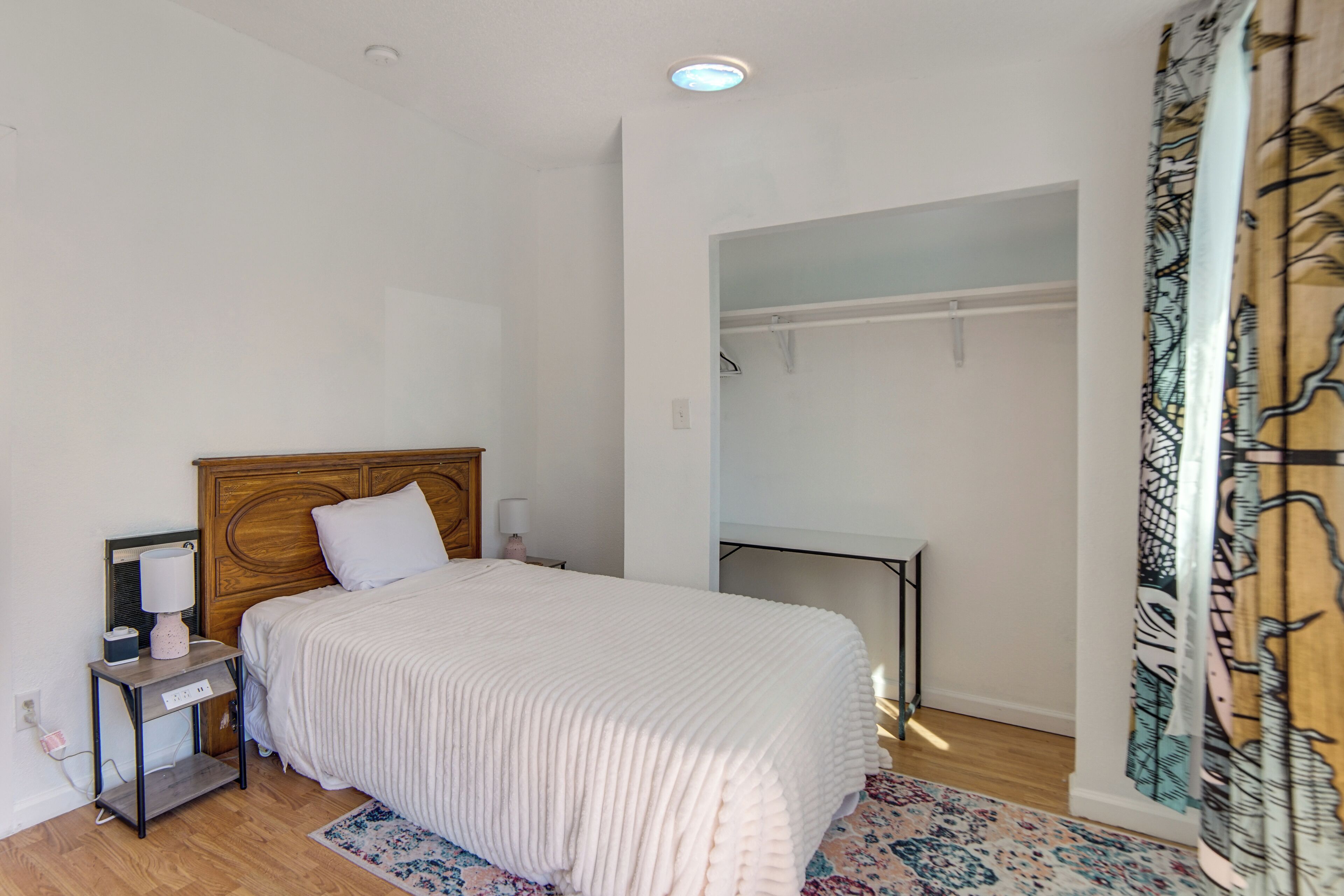 Une chambre à coucher avec un lit, une table de chevet, une lampe et un rideau à motifs.