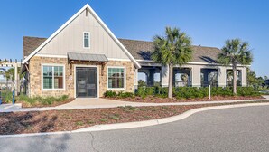 A two-story building with a stone facade, a metal roof, and a covered porch area with palm trees.