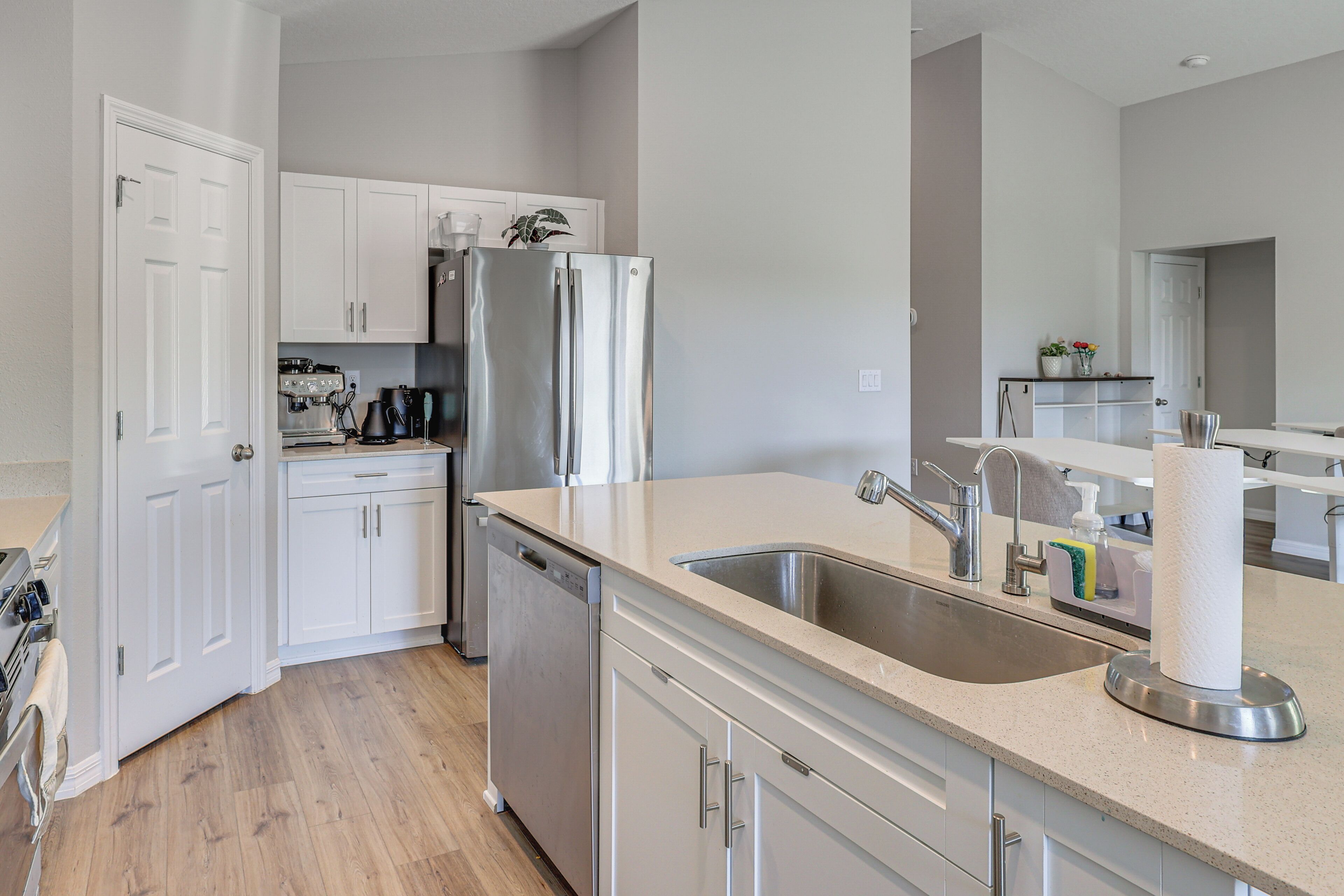 A modern kitchen with white cabinetry, stainless steel appliances, and a large sink.