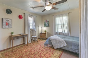 A bedroom with a bed, a desk, a chair, a ceiling fan, and a window with curtains. - Cozy & Cute Crystal City Home: Shaded Deck w/ BBQ (Crystal City)