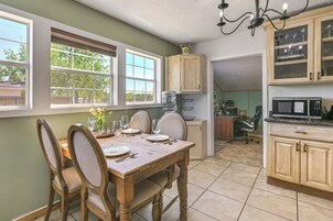 Un comedor con una mesa y sillas de madera, una cocina con armarios y un microondas, y una vista por la ventana.