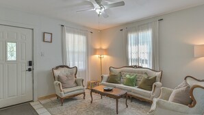 Un salon avec un ventilateur de plafond, deux fauteuils, un canapé, une table basse et un lampadaire.