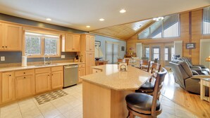 A spacious kitchen with wooden cabinets, a central island, and a dining area with chairs.