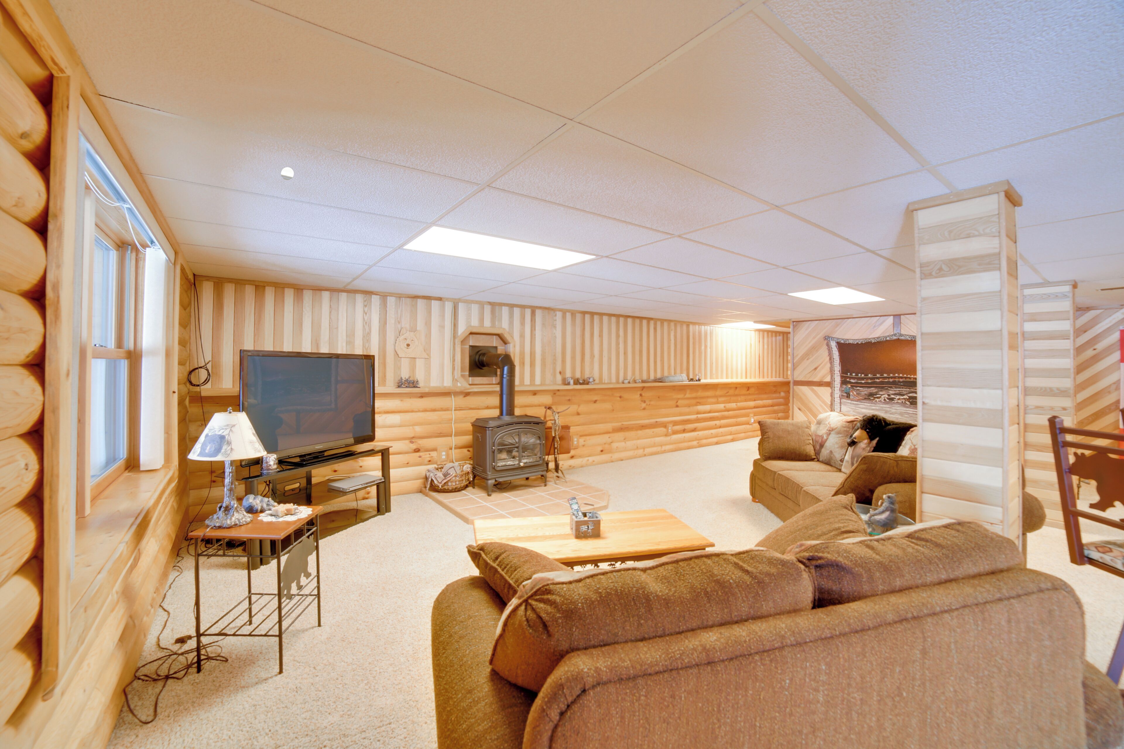 A log cabin interior with a television, sofa, and fireplace.