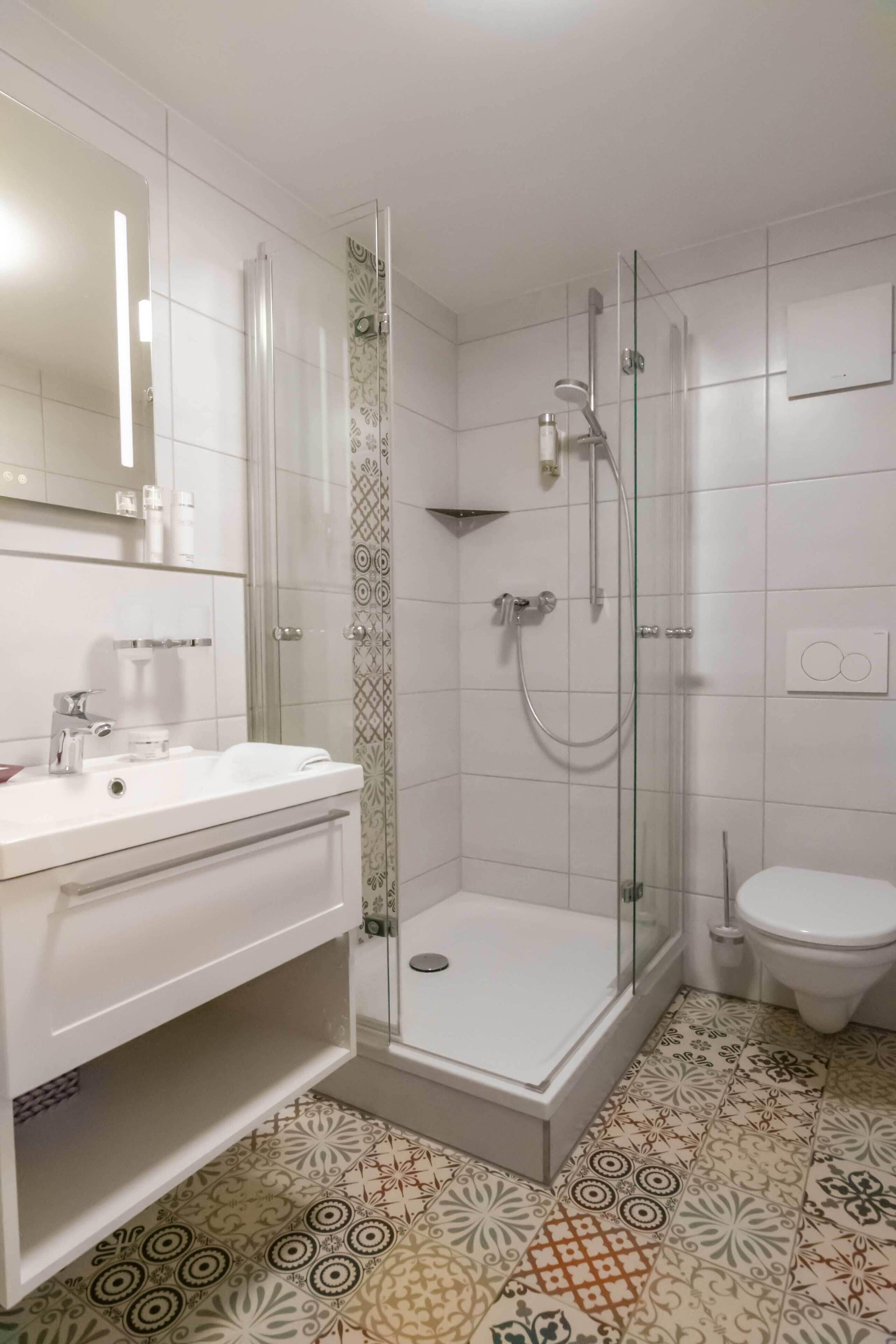 Een badkamer met douche, toilet en wastafel.