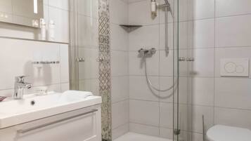 Een badkamer met douche, toilet en wastafel.