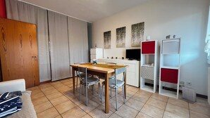 Un espace de vie compact comprenant une table à manger, des chaises, un coin cuisine, une armoire et un téléviseur.