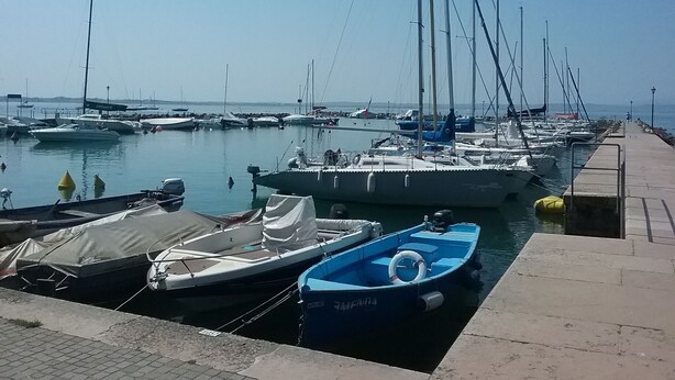 Un port de plaisance où sont amarrés différents types de bateaux, un ciel dégagé et une mer calme.