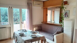 Un coin repas avec une table dressée pour quatre personnes, un canapé, un radiateur et une fenêtre avec des rideaux.