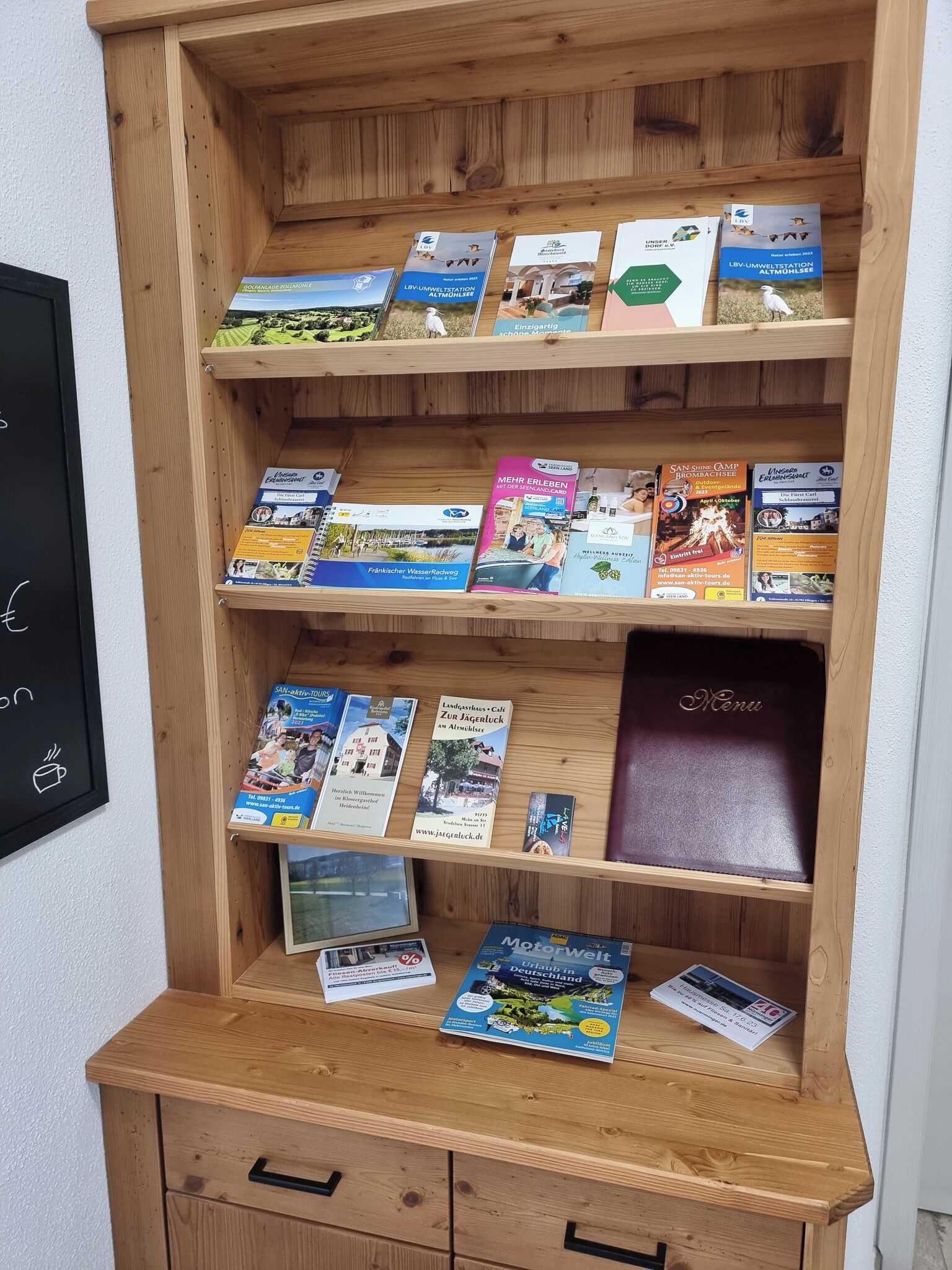 Een houten boekenkast met verschillende reis- en informatieve boeken.