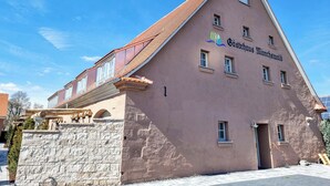Un bâtiment doté d’un toit en pente, de nombreuses fenêtres et d’un mur en pierre.