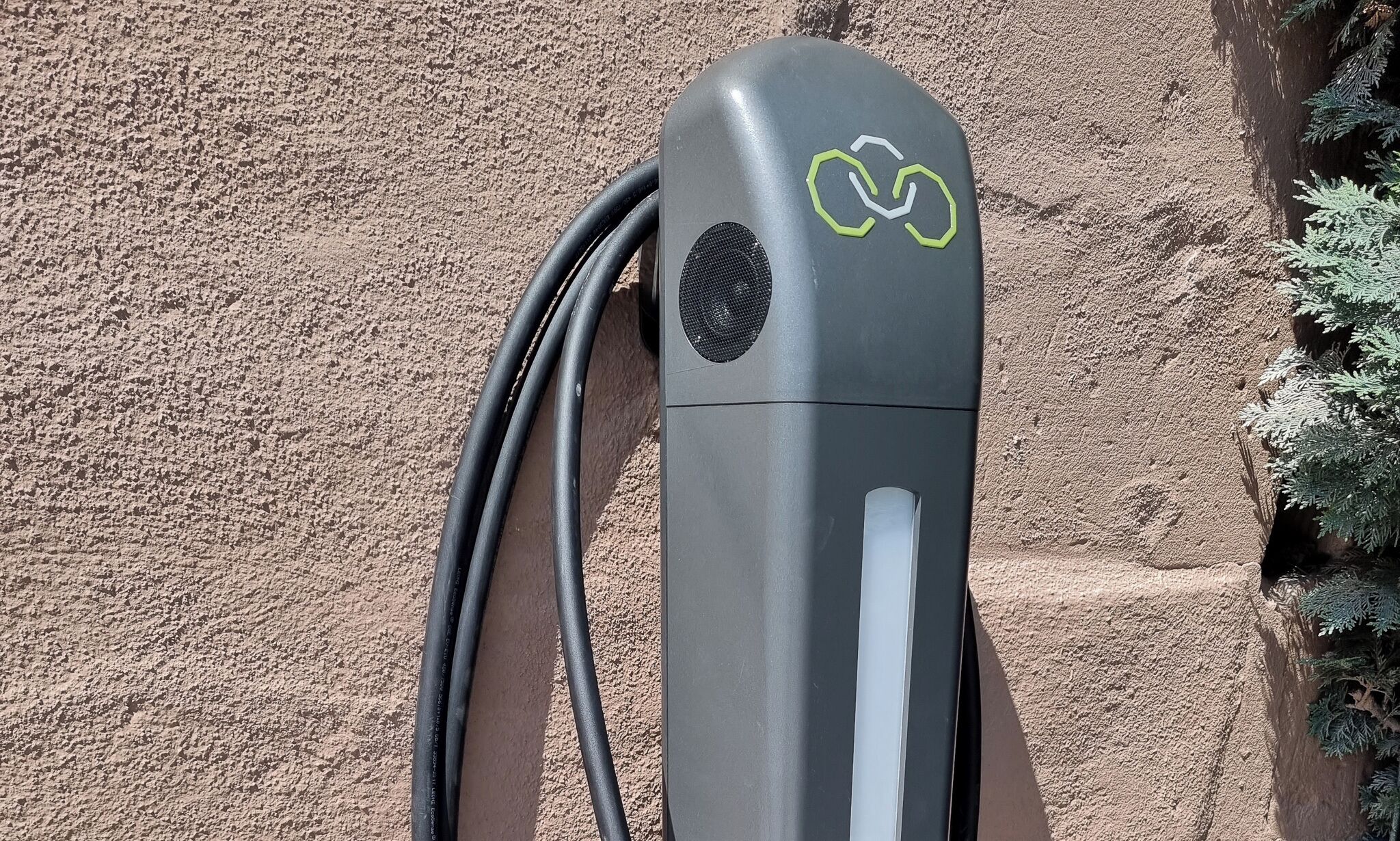 A charging station with a cable connected to it, set against a textured wall.
