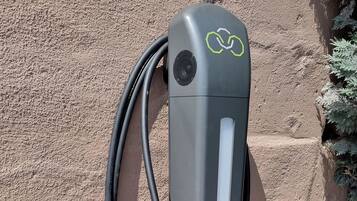 A charging station with a cable connected to it, set against a textured wall.
