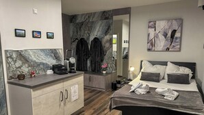 A modern hotel room with a bed, a small kitchenette, a marble backsplash, and a large mirror. - Day SPA Design Muhr - Muhr am See (Muhr am See)
