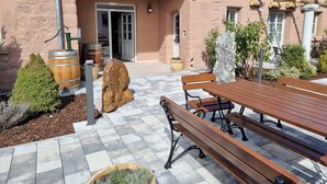 A patio with a wooden table and benches, a stone wall, and a building entrance. - Day SPA Design Muhr - Muhr am See (Muhr am See)