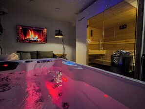 Una habitación moderna con bañera de hidromasaje, chimenea y sauna.